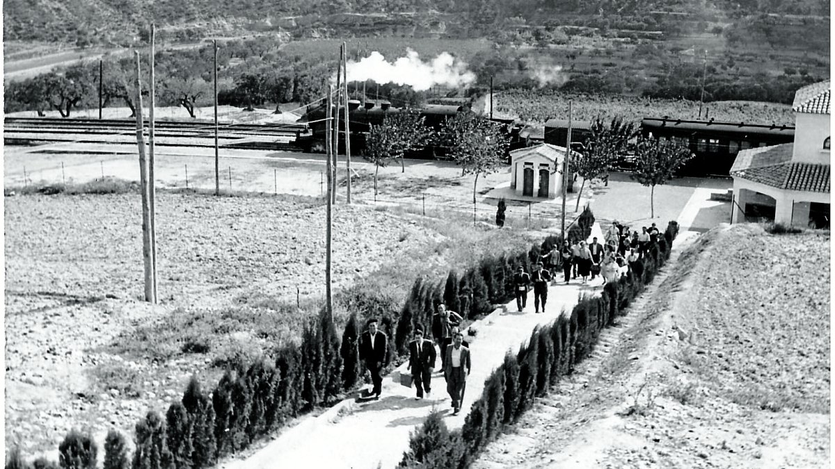 Viatgers baixant del tren de la línia de la Val de Zafán a l’estació de Bot, emprenent el camí a peu fins al poble.