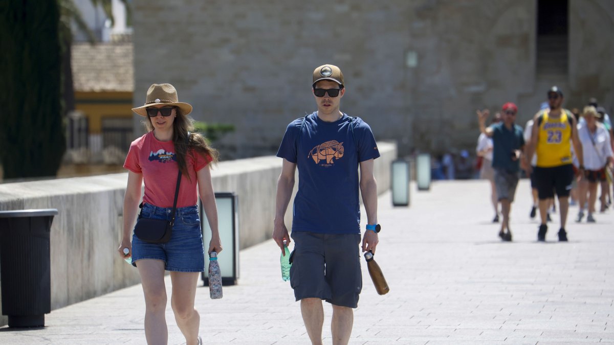 Turistas caminando con botellas de agua para aliviar las altas temperaturas.