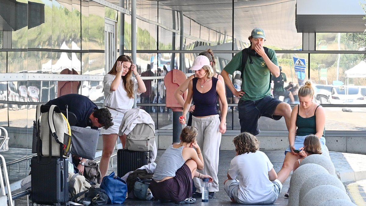 Un grup de turistes espera l'arribada d'un taxi aquest dissabte al migdia.