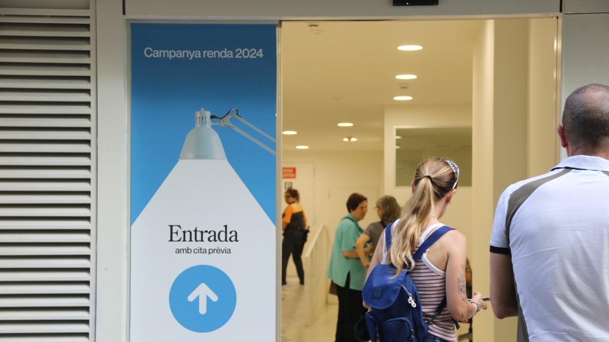 Personas haciendo cola en una oficina de la Agencia Tributaria de Catalunya (ATC) para recibir atención presencial y realizar la declaración de la renta