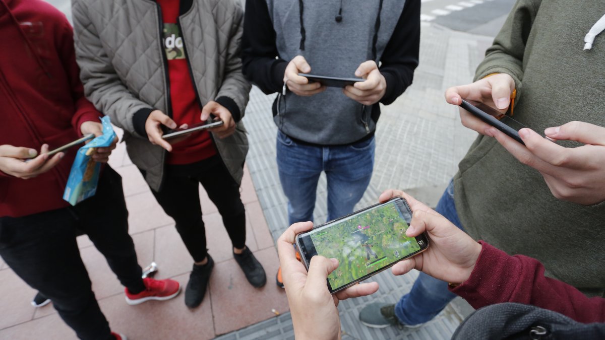 Varios jóvenes de Tarragona juegan a Fortnite en el móvil.