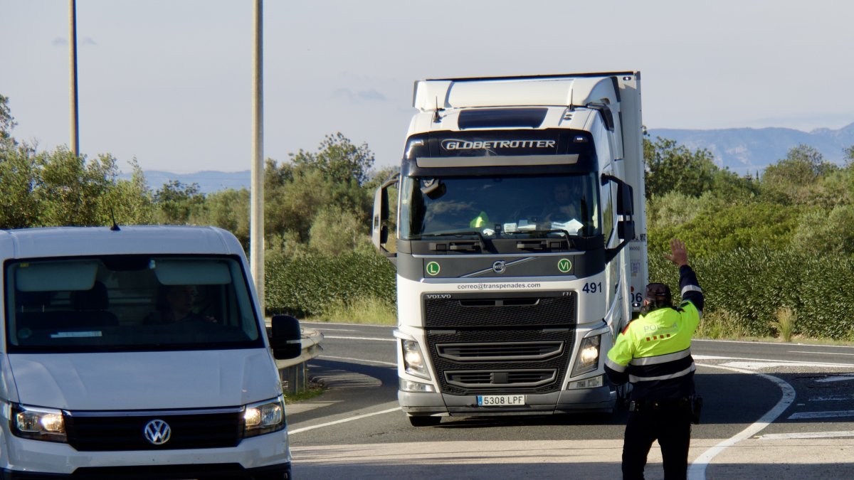 Uno de los agentes pide a un camión que se diriga a la zona de control de Mossos en el área de L'Aldea
