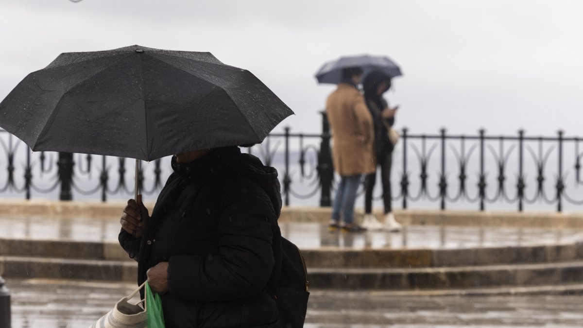 Peatones a la altura del Balcó del Mediterrani con paraguas en la mano.