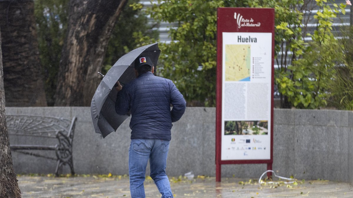 Un hombre se protege del viento y la lluvia este sábado en Huelva.