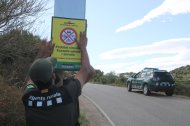 Un agente rural coloca un cartel para advertir del cierre de paso a las zonas boscosas.