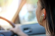 Una mujer conduce con un auricular en la oreja. La normative lo prohíbe.