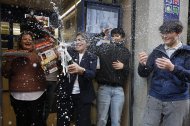 Varias personas celebran a las puertas de la administración de loterías del número 10 de la calle Barquillo, en Madrid, donde se ha vendido íntegramente el segundo premio.