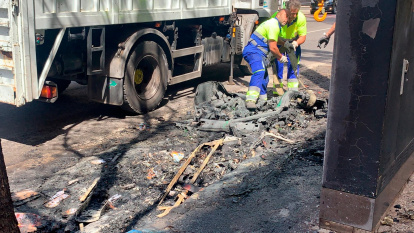 Operarios trabajando en la retirada de restos de contenedores quemados, esta mañana.