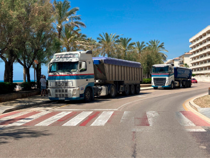 Los camiones con la arena van por la vía pública.